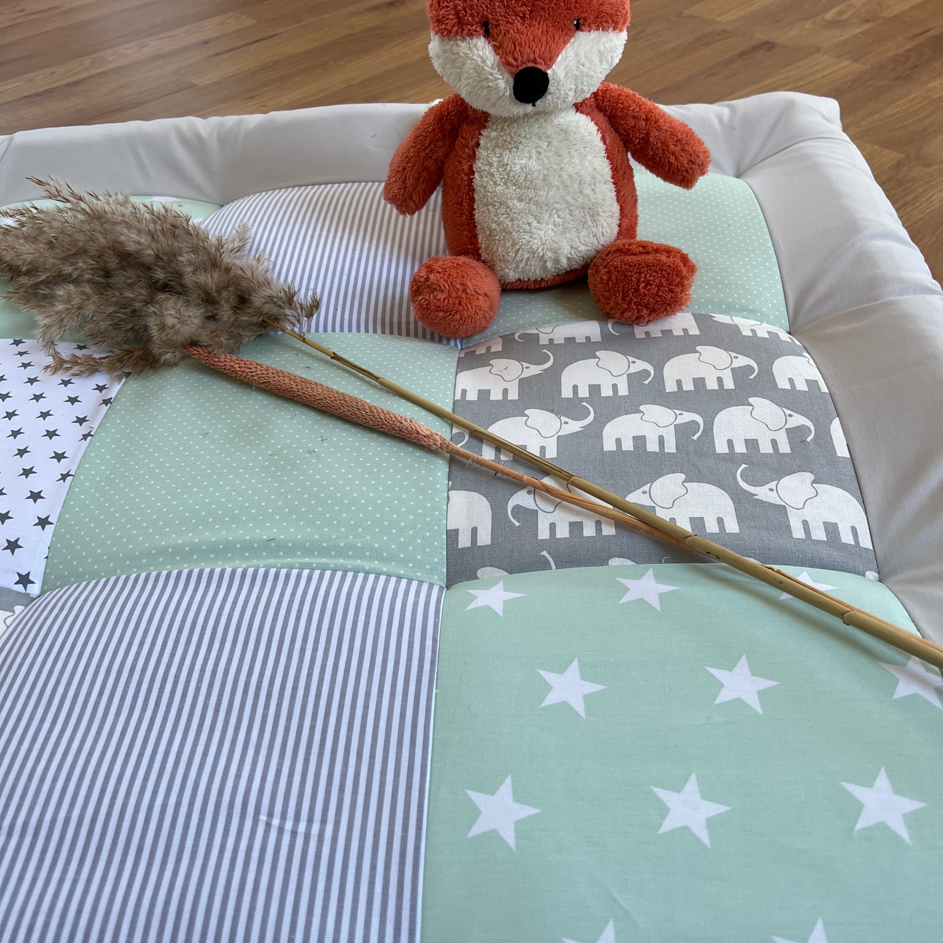A red stuffed fox toy sits atop a quilt with a blue and white striped pattern and white stars.