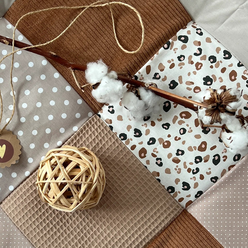 a patchwork quilt with various textures and patterns, including a branch, a round ball, and a heart-shaped tag.