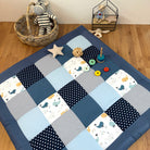 A blue and white quilt with a star pattern, a basket with a stuffed animal, and various toys on a wooden floor.