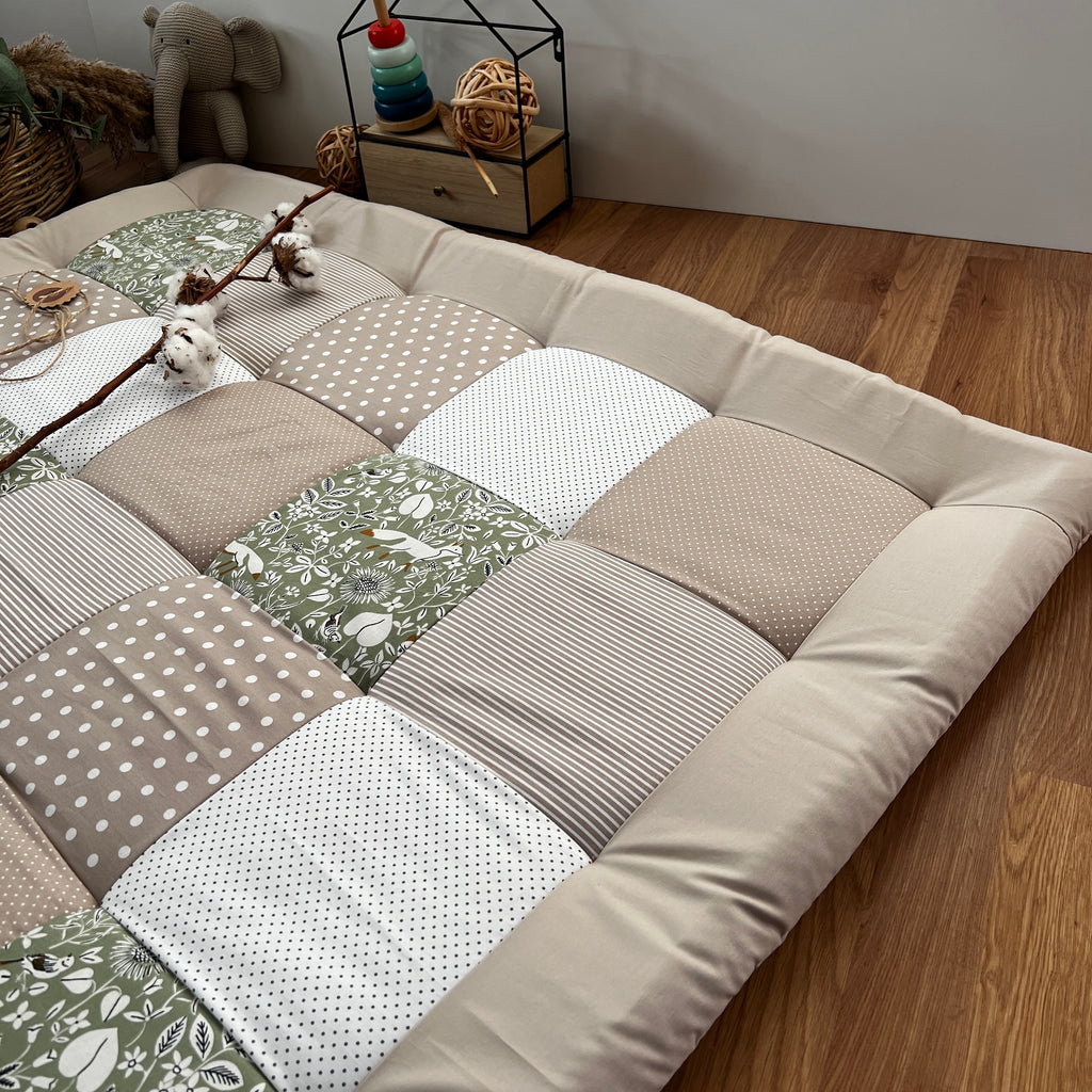 a patchwork quilt or mat with a variety of colors and patterns, including polka dots, stripes, and floral designs, laid out on a wooden floor.