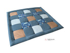 A quilted bed mat with a patchwork design of various colors and patterns, including polka dots, stripes, and animal motifs.